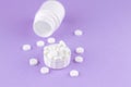 Close up white pill bottle with spilled out pills and capsules in cap on purple background with copy space. Focus on foreground, s Royalty Free Stock Photo