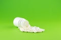 Close up white pill bottle with spilled out pills and capsules on green background with copy space. Focus on foreground, soft boke Royalty Free Stock Photo