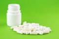 Close up white pill bottle with spilled out pills and capsules on green background with copy space. Focus on foreground, soft boke Royalty Free Stock Photo