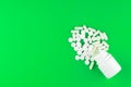 Close up white pill bottle with spilled out pills and capsules on lime green background with copy space. Focus on foreground, soft Royalty Free Stock Photo