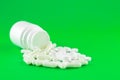 Close up white pill bottle with spilled out pills and capsules on lime green background with copy space. Focus on foreground, soft Royalty Free Stock Photo