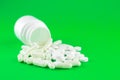 Close up white pill bottle with spilled out pills and capsules on lime green background with copy space. Focus on foreground, soft Royalty Free Stock Photo