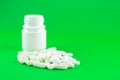 Close up white pill bottle with spilled out pills and capsules on lime green background with copy space. Focus on foreground, soft Royalty Free Stock Photo