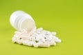 Close up white pill bottle with spilled out pills and capsules on pear yellow background with copy space. Focus on foreground, sof Royalty Free Stock Photo