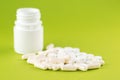 Close up white pill bottle with spilled out pills and capsules on pear yellow background with copy space. Focus on foreground, sof Royalty Free Stock Photo