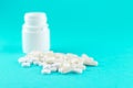 Close up white pill bottle with spilled out pills and capsules on turquoise background with copy space. Focus on foreground, soft Royalty Free Stock Photo