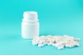 Close up white pill bottle with spilled out pills and capsules on turquoise background with copy space. Focus on foreground, soft Royalty Free Stock Photo