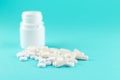 Close up white pill bottle with spilled out pills and capsules on turquoise background with copy space. Focus on foreground, soft Royalty Free Stock Photo