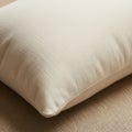A close-up of a white pillow resting on a textured beige fabric surface. The pillow\'s Royalty Free Stock Photo