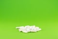 Close up white pills and capsules on green background with copy space. Focus on foreground, soft bokeh. Pharmacy drugstore concept Royalty Free Stock Photo