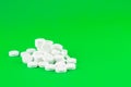 Close up white pills on lime green background with copy space. Focus on foreground, soft bokeh. Pharmacy drugstore concept Royalty Free Stock Photo