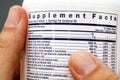 Close-up of white plastic jar with supplement facts of multivitamins in hands Royalty Free Stock Photo