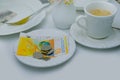 Close-up of white plate for money, Swiss francs banknotes and coins, Restaurant bill, cup of coffee, delicate pink flowers, dishes