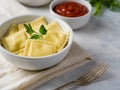 Close-up is a white plate with mouth-watering ravioli garnished with a sprig of parsley. Also in the frame is a gravy boat with Royalty Free Stock Photo