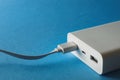 Close-up of white power bank and cable in usb port on blue background Royalty Free Stock Photo