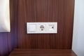 A close-up of white power socket, power outlet plug and light switch on a wooden panel wall Royalty Free Stock Photo