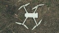 Close-up of white quadrocopter on ground in grass. Modern drone unmanned aerial vehicle with propellers. Royalty Free Stock Photo