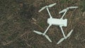 Close-up of white quadrocopter on ground in grass. Modern drone unmanned aerial vehicle with propellers. Royalty Free Stock Photo