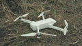 Close-up of white quadrocopter on ground in grass. Modern drone unmanned aerial vehicle with propellers. Royalty Free Stock Photo