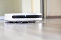 close-up of a white robot vacuum cleaner automatically cleaning the white wool of the house. horizontal Royalty Free Stock Photo