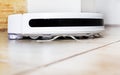 close-up white robot vacuum cleaner performs automatic cleaning in the house. horizontal Royalty Free Stock Photo