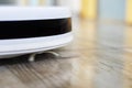 close-up of a white robot vacuum cleaner performs automatic cleaning in a house in a scandinavian interior. horizontal Royalty Free Stock Photo