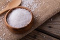Close-up of white rock salt in wooden bowl by spoon on jute fabric at table