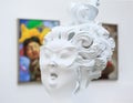 Close-up of a white sculpture with a blurred colorful painting on the background.