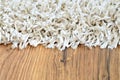 Close-up of white shaggy carpet on brown wooden floor Royalty Free Stock Photo