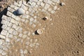 Close up of white stone slabs formed into a mosaic covered with beach sand and seashells. Broken tiles mosaic seamless pattern Royalty Free Stock Photo