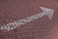 Close-up of white straight road marking arrow on maroon paving flag Royalty Free Stock Photo