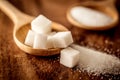 Close up white sugar cubes and cane in wooden spoon on the table Royalty Free Stock Photo