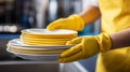 Close up of white tableware girl wearing yellow gloves washing dishes in bright industrial kitchen