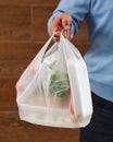 Close up of white transparent plastic bag with food in hand of unknown man.