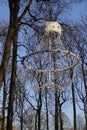 Close up of white unusual interesting shape lantern or lamp hanging on trees with almost no leaves. Lamp made of