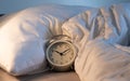 Close up the vintage clock 10.10 o`clock 10pm in the bed with white blanket, bedroom background Royalty Free Stock Photo