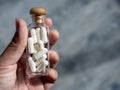 Close up white vitamins or supplements in the small clear glass bottle vials in person`s hand. Royalty Free Stock Photo