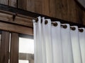 Close-up of white wall curtain on wooden curtain rail bar decorated on the wood plank wall of tropical gable building. Royalty Free Stock Photo