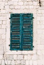 Close-up of a white wall with a window closed with old shabby blue paint shutters. Royalty Free Stock Photo