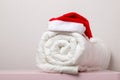 Close-up of white warm duvet roll with a cap of Santa Claus on the table against the background of light wall Royalty Free Stock Photo
