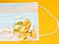 Close-up of white and yellow pills on  medical mask. intence yellow paper background Royalty Free Stock Photo