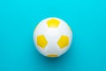Close-up of white and yellow soccer ball in centre of turquoise blue background Royalty Free Stock Photo