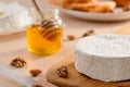 Close up on a whole brie cream cheese, nuts and jar of honey on kitchen table