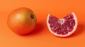 Close-up of a whole and a slice of red grapefruit on an orange background Royalty Free Stock Photo