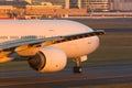 Close up of wide-body passenger aircraft with wing and engine taxing on the runway during sunset. Airplane turns on runway Royalty Free Stock Photo