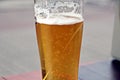 A glass of cold beer standing on a red table against the backdrop of a yacht Royalty Free Stock Photo