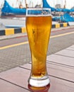 A glass of cold beer standing on a red table against the backdrop of a yacht Royalty Free Stock Photo