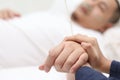 Close up of wife holds hand of her husband who is sick and sleep on bed in hospital, sad emotional moments Royalty Free Stock Photo