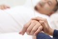 Close up of wife holds hand of her husband who is sick and sleep on bed in hospital, sad emotional moments