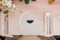 Wedding dinner table reception. Close-up of wildcard with gold beads, transparent glass. Runner of pink silk. Candles in Royalty Free Stock Photo